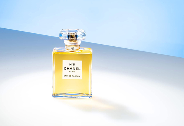 Luxury Chanel No. 5 perfume bottle photographed with soft studio lighting and minimalist blue-toned background for high-end commercial beauty photography.