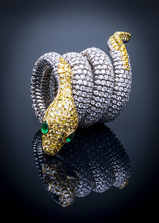 Luxury Serpenti diamond cuff photographed with precision studio lighting and reflective black surface for high-end jewelry photography.